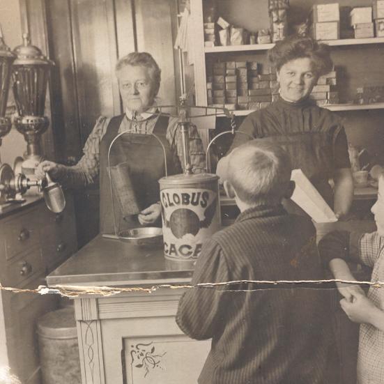 Sort-hvid foto: Kaffe-Karen og hendes mor betjener to børn i butikken.