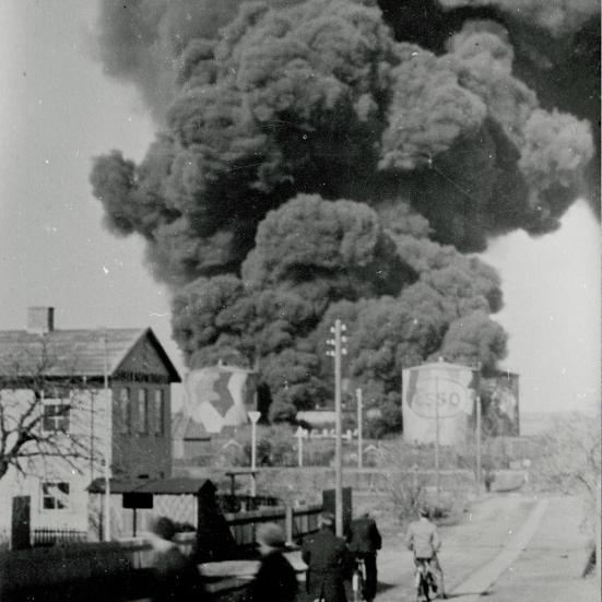 Sort-hvid foto: Røgsky stiger op fra brændende siloer.