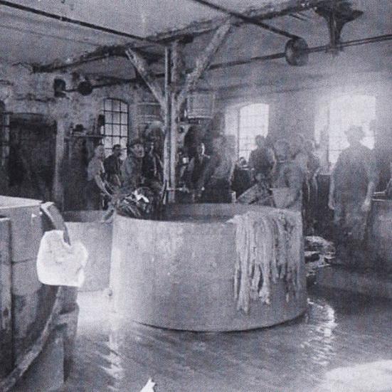 Sort-hvid foto: En gruppe arbejdere samlet om et stort kar.