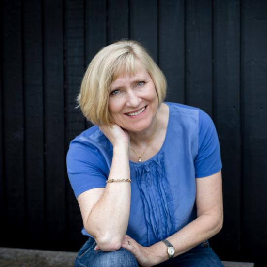 Foto af Pernille Juhl i blå trøje på sort baggrund. 
