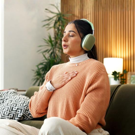 Person med hovedtelefoner mediterer i en sofa.