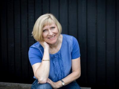 Foto af Pernille Juhl i blå trøje på sort baggrund. 