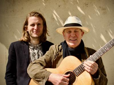 Foto af far og søn op af en mur med guitar en solskinsdag