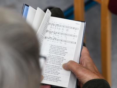 Foto oppefra af en person der har slået op i Højskolesangbogen