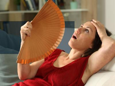 Kvinde, der sidder i en sofa og vifter sig med en håndvifte.