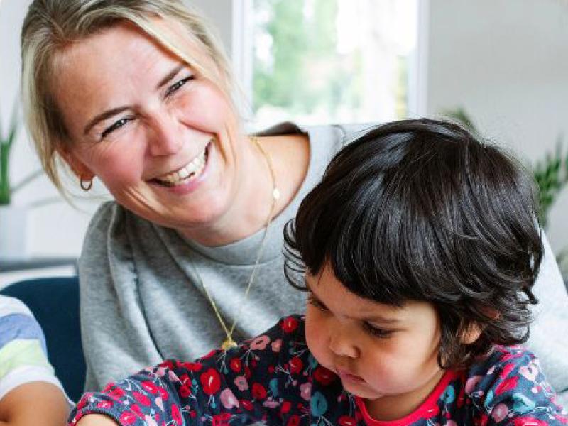 Kvinde med barn ved bord.