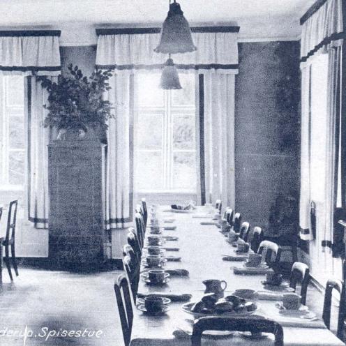 Sort-hvid foto: Spisestuen på Rekonvalescenthjemmet. Langborde med hvide duge dækket op med service.