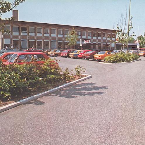 Gammelt farvefoto af Holbæk Station set fra parkeringspladsen på Jernbane Plads.