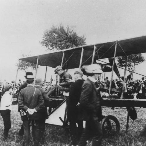 Sort-hvid foto af folk foran en dobbeltdækkerflyver.