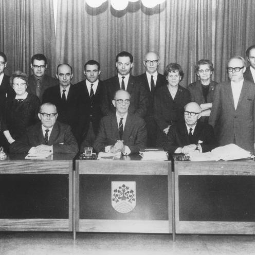 Sort-hvid foto af byrådet opstillet bag en siddende borgmester.