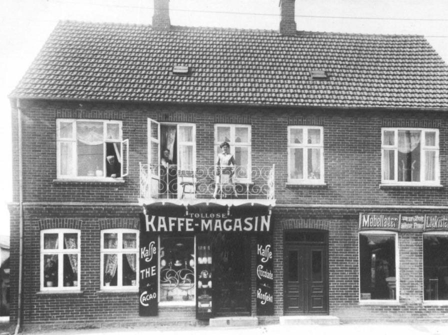 Sort-hvid foto: Tølløse Kaffe-Magasin, Jernbanevej 6, hvor Karen står på altanen og moren i døren.