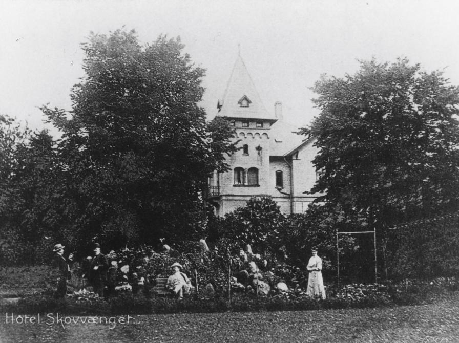 Sort-hvid postkort med hotellets tårn og gæster i haven foran.