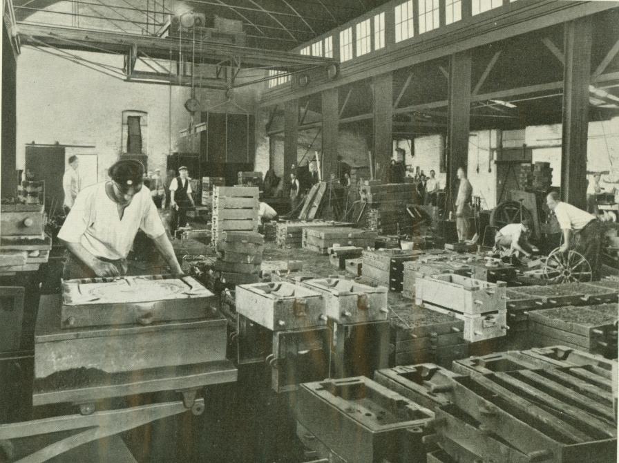 Sort-hvid foto af fabrikshal med arbejdere.